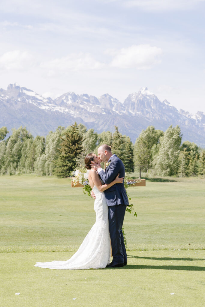 Bride and groom kissing in front of mountain views during a Grand Teton wedding ceremony