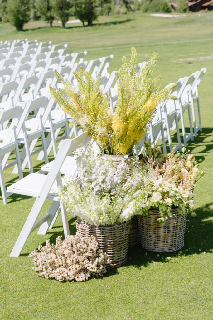 Ceremony seating with white chairs and floral arrangements set up outdoors for a Grand Teton wedding