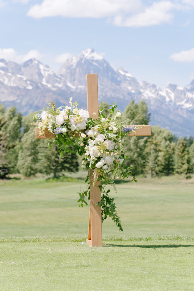 Wooden ceremony cross decorated with flowers set against Grand Teton mountains at a Grand Teton wedding