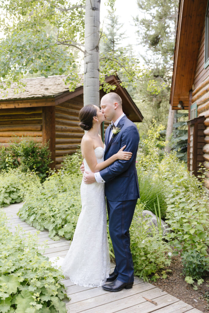 Bride and groom kissing behind are some cabins during a Grand Teton wedding ceremony