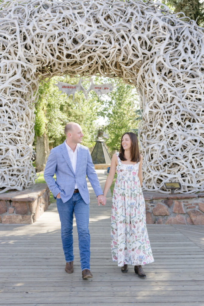 Couple holding hands under the antler arches in Jackson Hole during a Grand Teton wedding celebration
