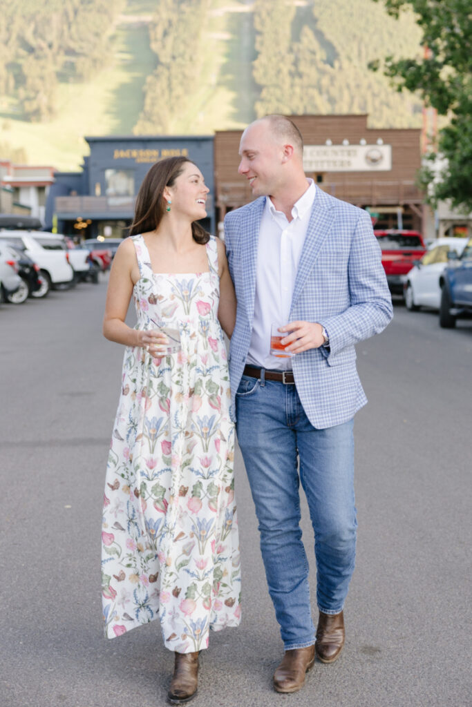 Couple walking together in downtown Jackson Hole holding drinks during a Grand Teton wedding weekend