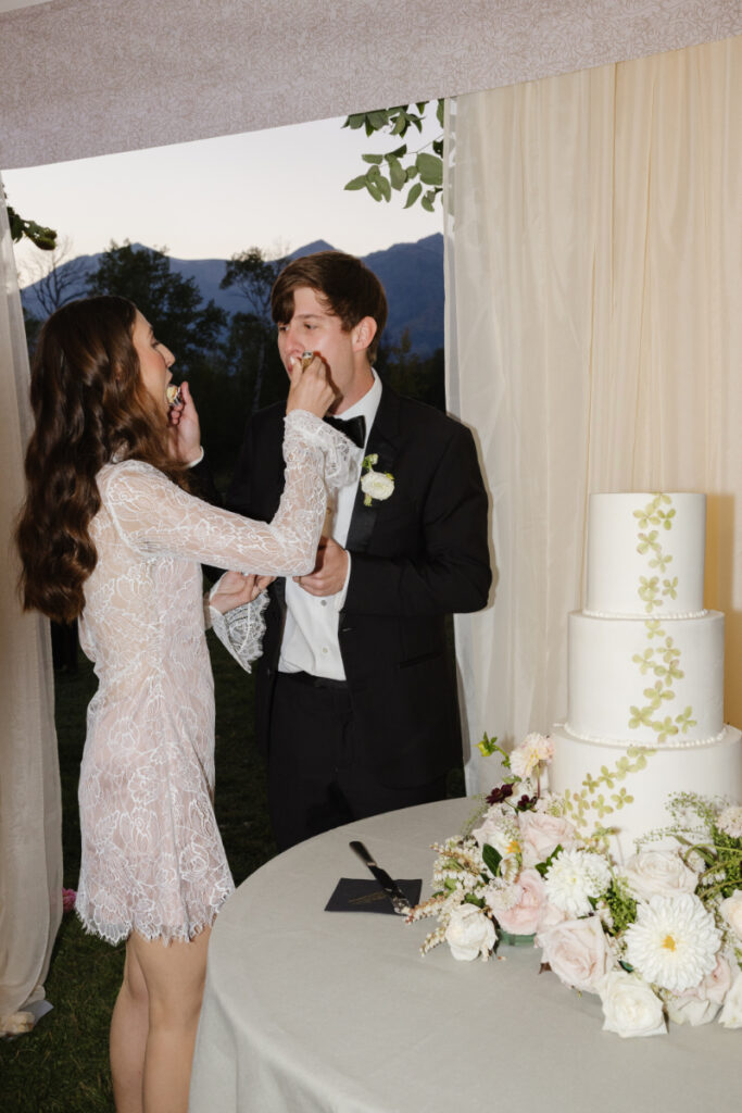Bride and groom feeding each other cake during a Grand Teton wedding reception celebration