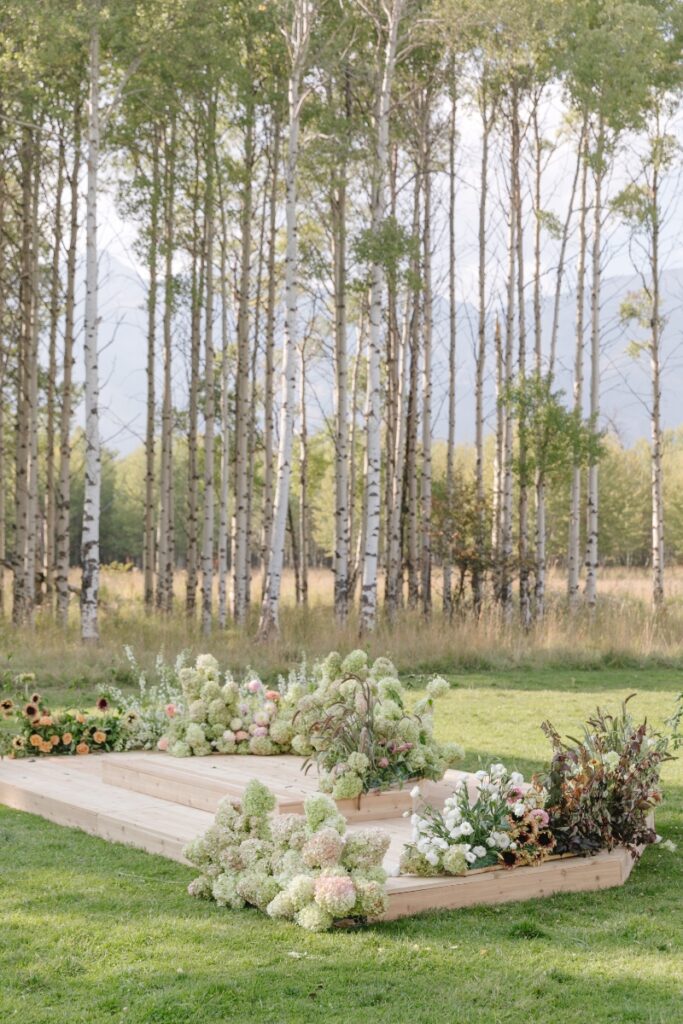 Outdoor wedding ceremony platform with floral arrangements and aspen trees, Jackson Hole Photographers