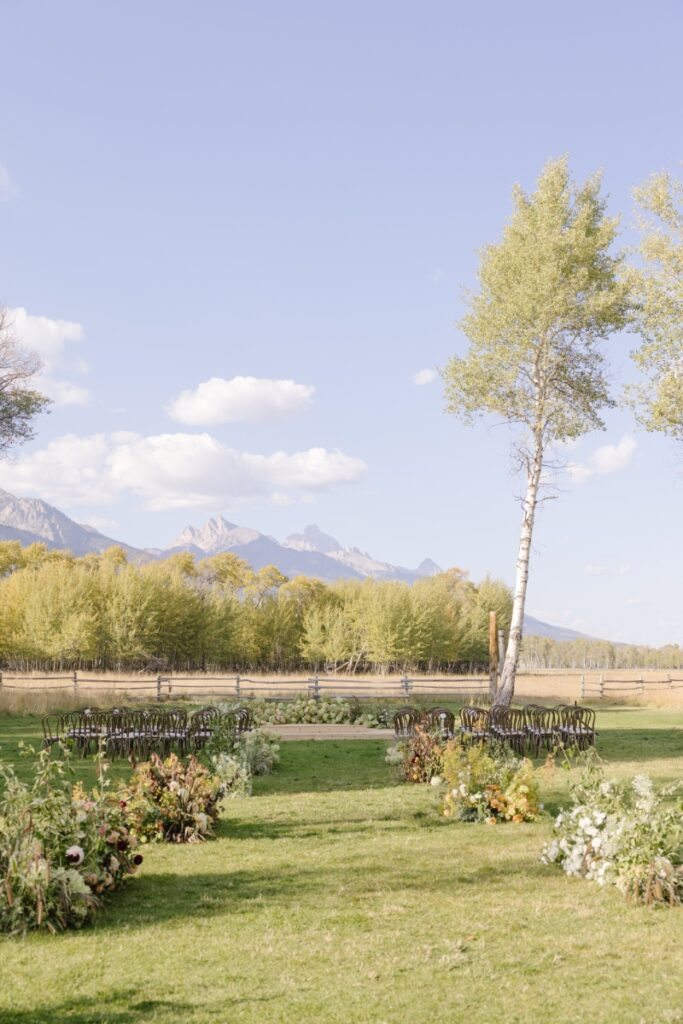 Outdoor wedding ceremony setup with mountain backdrop and floral aisle, Jackson Hole Photographers