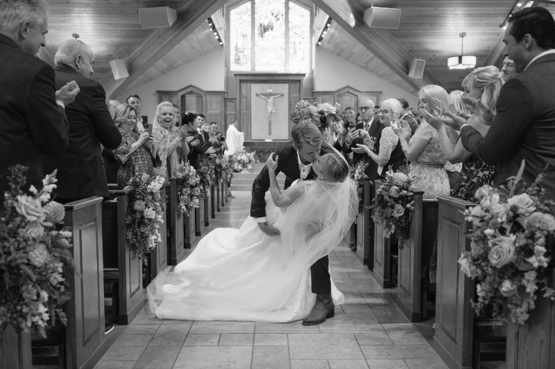Groom dipping the bride for a kiss and the cathedral in Snake River.