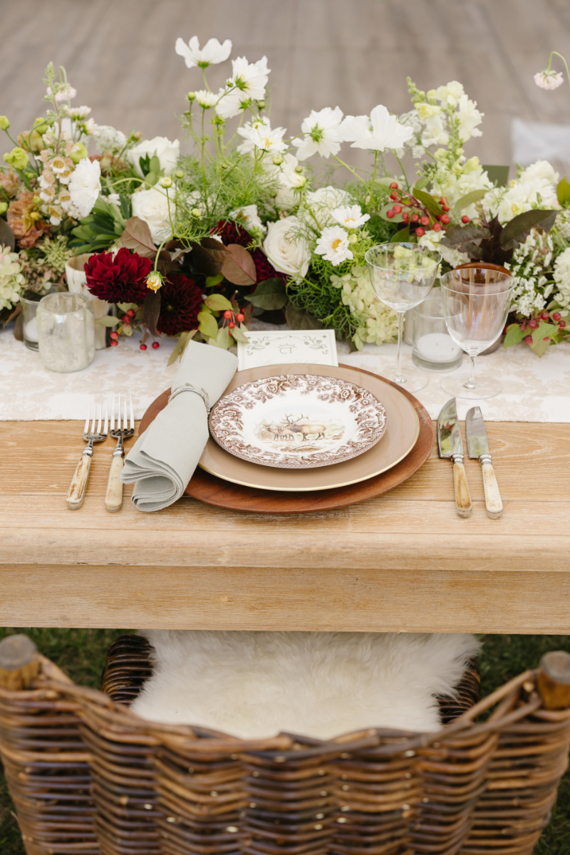 Elegant wedding tablescape with floral centerpiece, vintage plate setting, and rustic wooden table