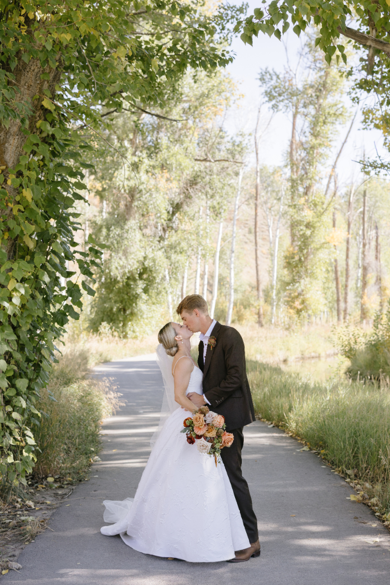 Bride and Groom kissing through a path as Snake River overlooks the Teton mountains.