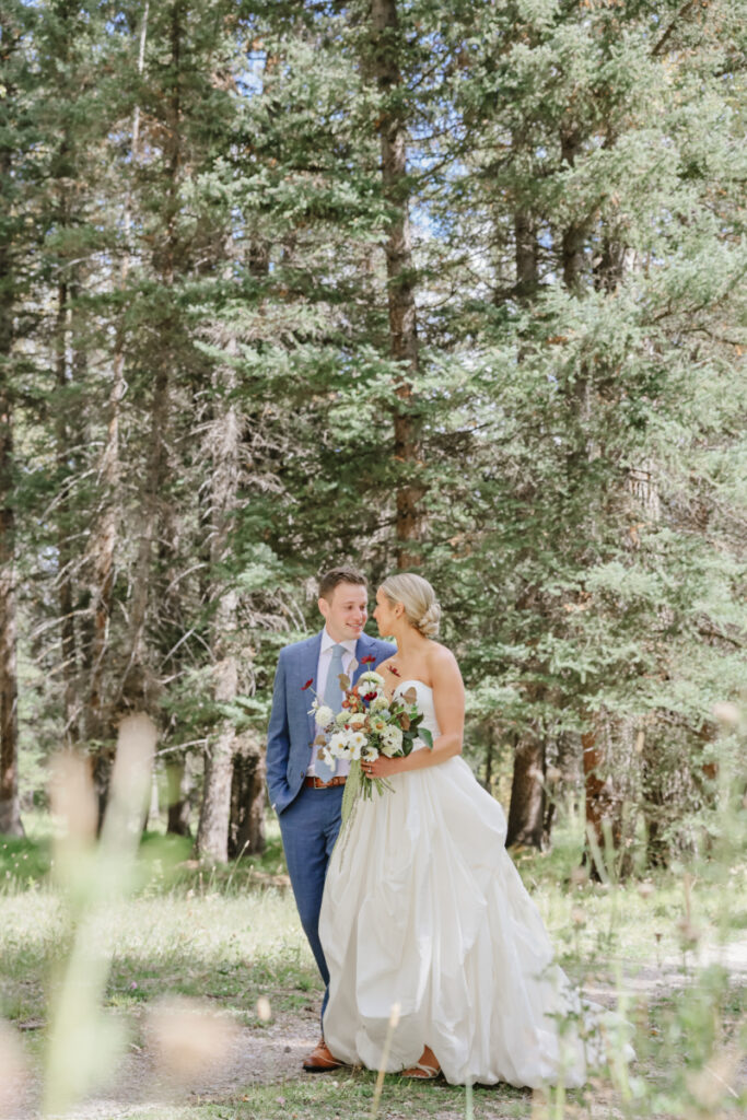 Bride and groom walking through a forest at a Jackson Hole dude ranch wedding