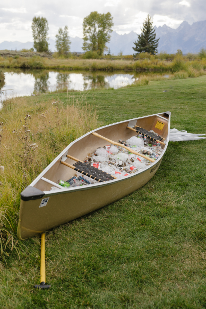 Canoe filled with drinks by a river at a Jackson Hole dude ranch wedding