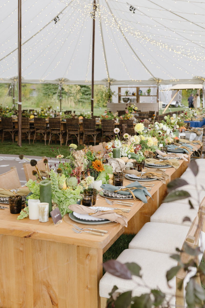 Reception tent with long tables and floral arrangements at a Jackson Hole ranch wedding