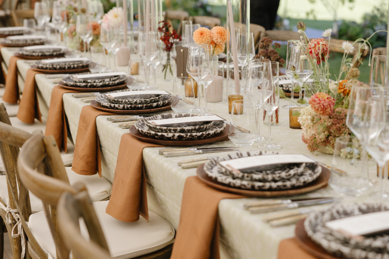 Documentary style wedding photography of an elegant reception tablescape with layered linens, patterned plates, and natural florals in Jackson Hole