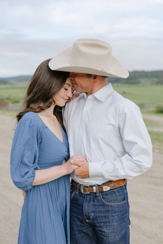 Couple embracing on a quiet country road during romantic lake engagement photos in a mountain landscape