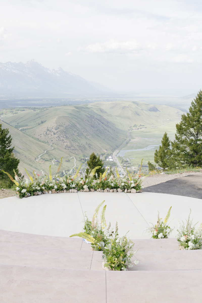 Luxury destination wedding in the mountains with floral ceremony design overlooking the Tetons and sweeping Jackson Hole valley views.