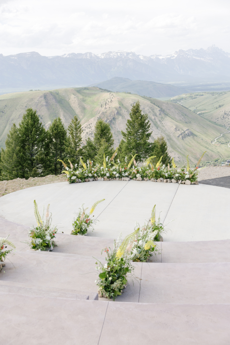Outdoor destination wedding in the mountains featuring an elevated ceremony space with panoramic Grand Teton views and wildflower-inspired florals.