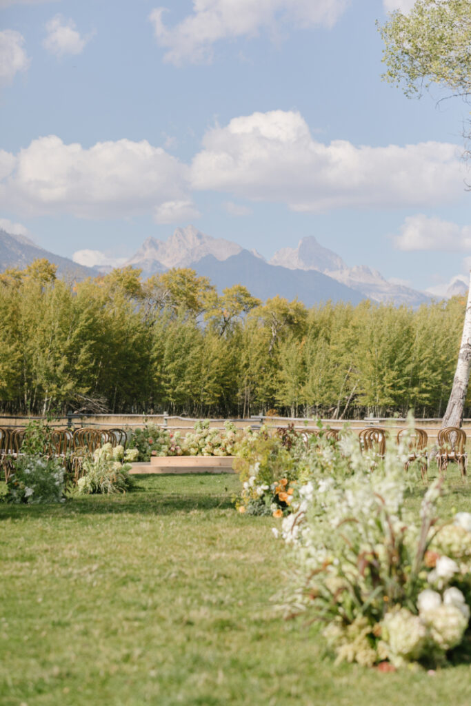 Elegant outdoor destination wedding in the mountains with floral arrangements, mountain scenery, and Grand Teton views in Wyoming.