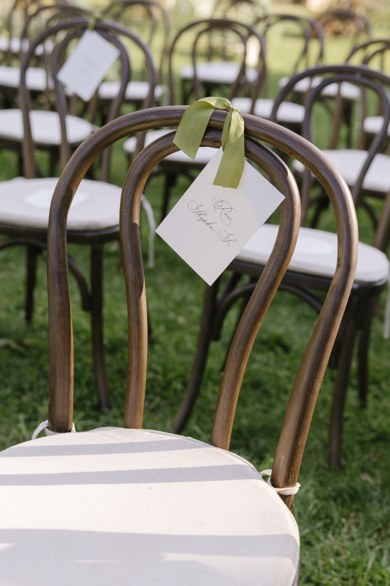 Brown wooden chairs set for a mountain ceremony, one tied with a green ribbon to mark reserved.