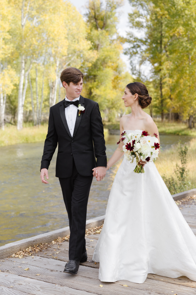 Bride and groom walking along a river during their Jackson Hole wedding, captured within a photography wedding timeline