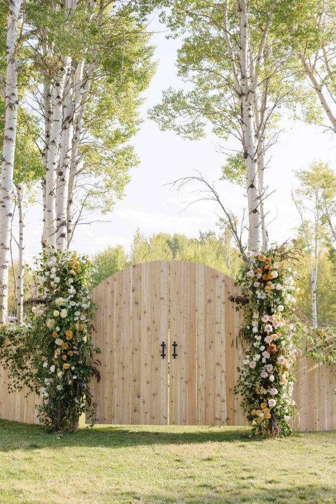 Wooden ceremony entrance with floral installations among trees at Jackson Hole wedding