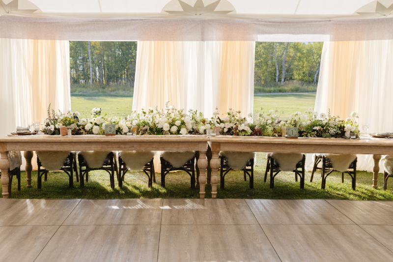 Elegant wedding reception table with floral arrangements under a tent in Jackson Hole
