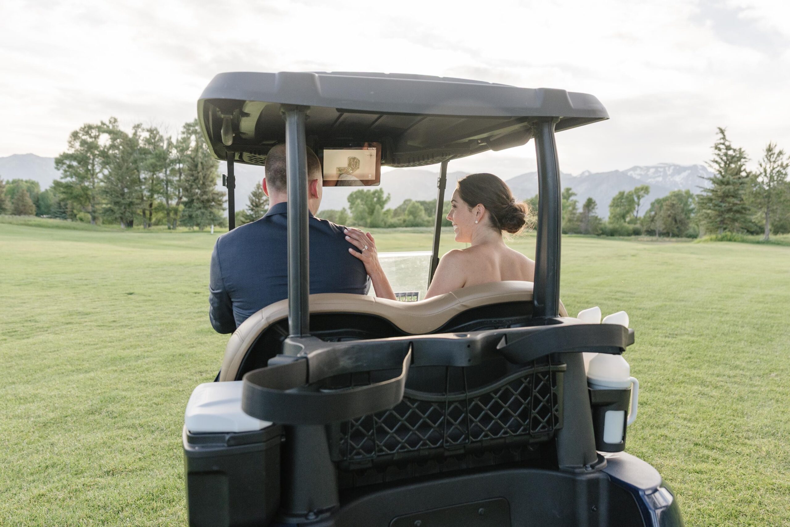 Newlyweds riding through Jackson Hole Golf and Tennis Club during sunset portraits.