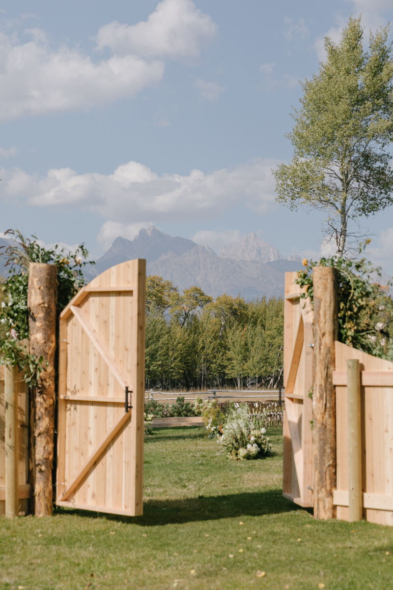 Snake River Ranch ceremony entrance with Teton Mountain views beyond custom wooden gates