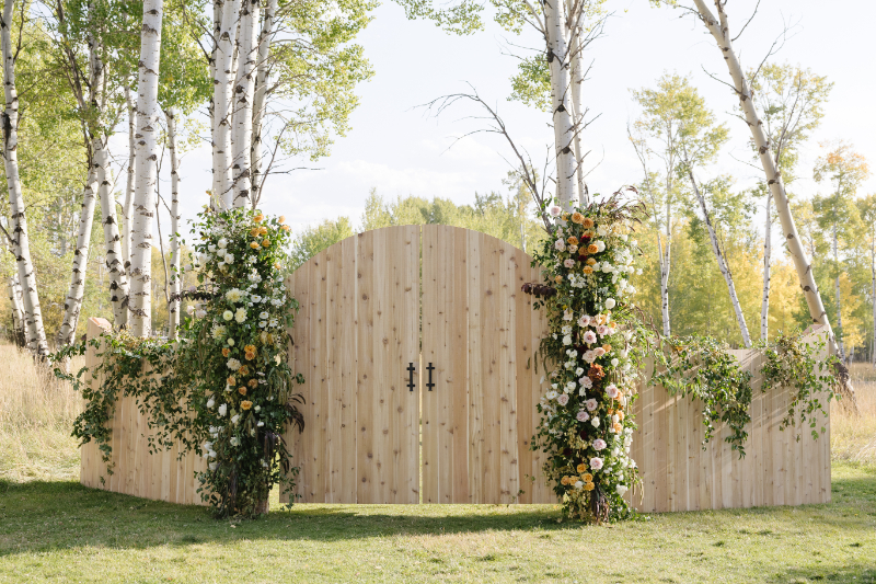 Ceremony entrance design at Snake River Ranch featuring custom wood gates and lush floral installations
