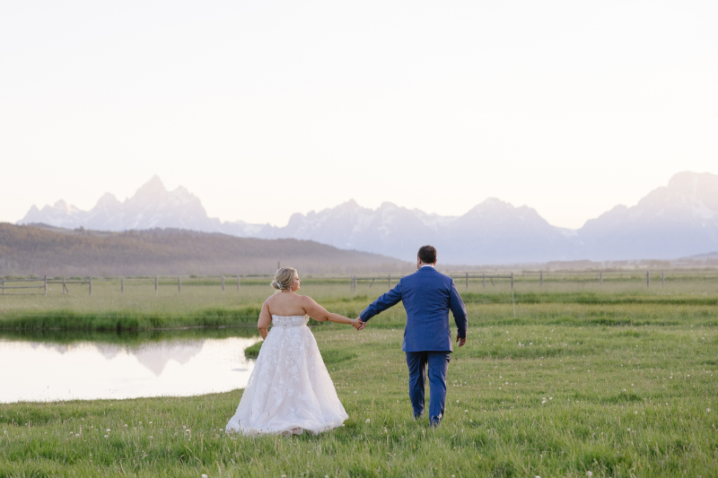 Blue hour photography in Jackson Hole with newlyweds walking beside a pond and the Grand Tetons
