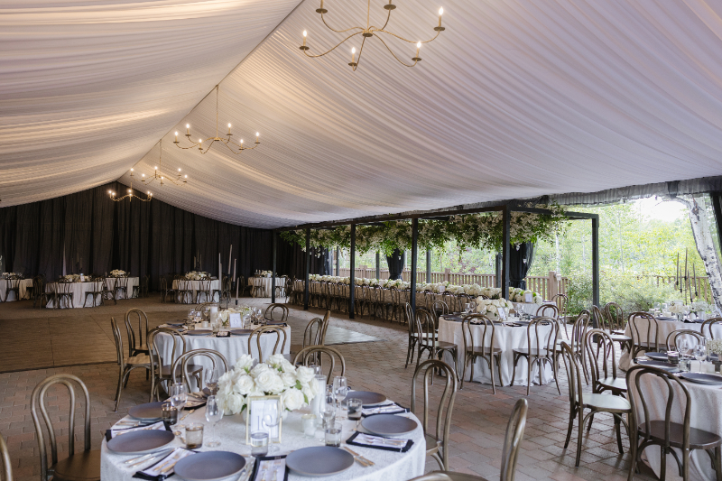 Reception tent with draped ceiling and candlelit tables at a Jackson Hole wedding
