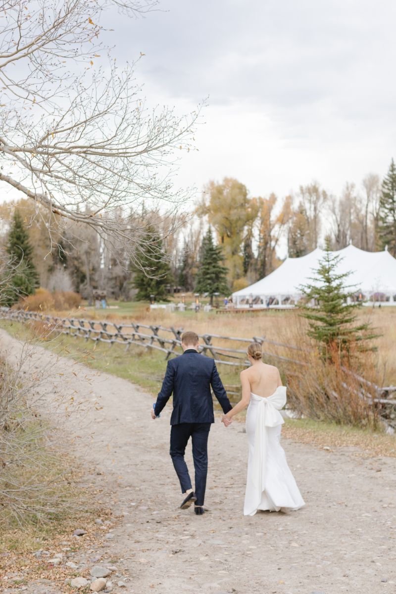 Bride and groom walking toward their fall wedding reception with Grand Teton views
