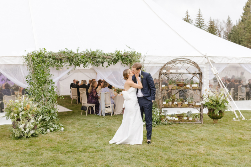 Bride and groom sharing a kiss outside their elegant fall wedding reception tent