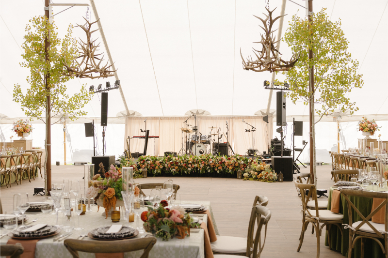 Reception stage with antler chandeliers inside the tent at Snake River Sporting Club wedding