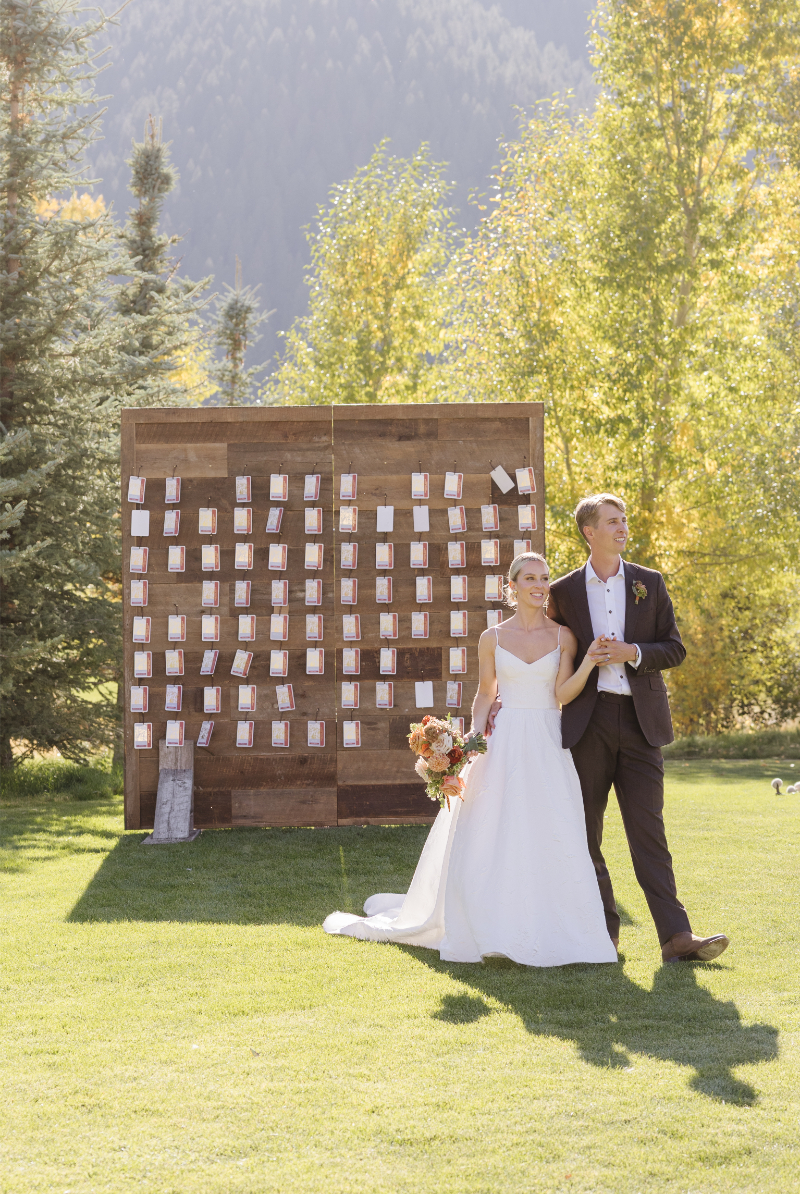 Bride and groom entering their Snake River Sporting Club wedding reception beside a seating chart display