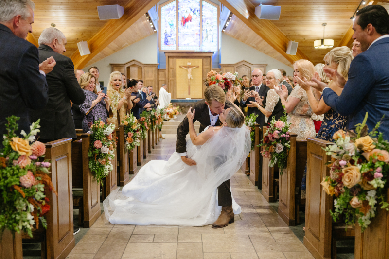 Bride and groom sharing a celebratory kiss after their Catholic wedding ceremony at Our Lady of the Mountains Catholic Church