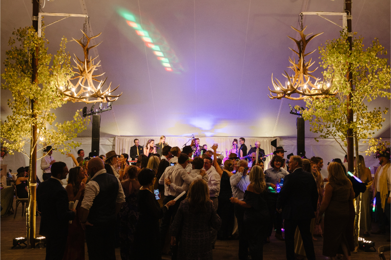 Guests dancing beneath antler chandeliers during a lively Snake River Sporting Club wedding reception