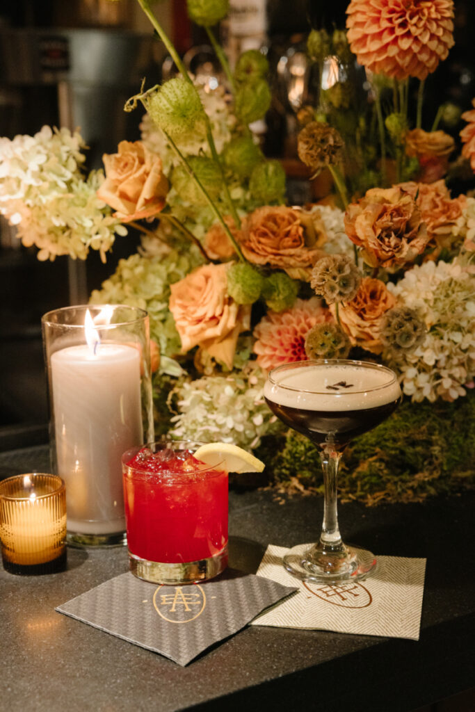 Espresso martini and signature cocktail displayed beside autumn floral arrangements at the wedding reception