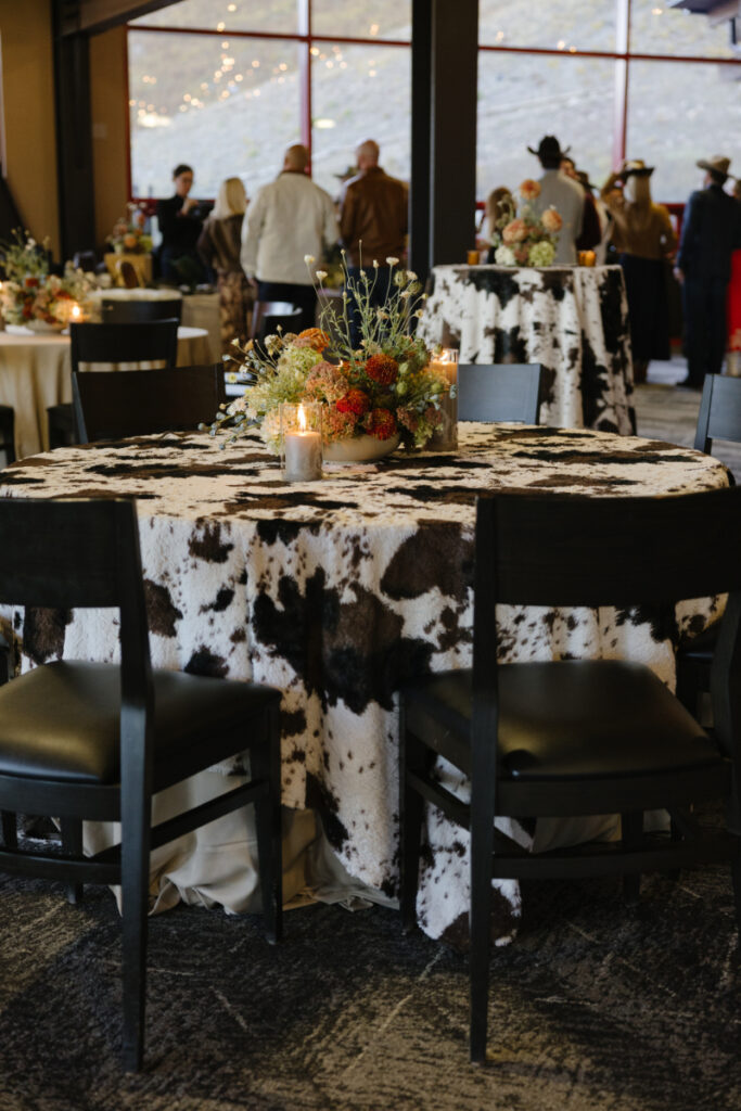 Western-inspired welcome party tables with cowhide linens and floral centerpieces at Rendezvous Lodge