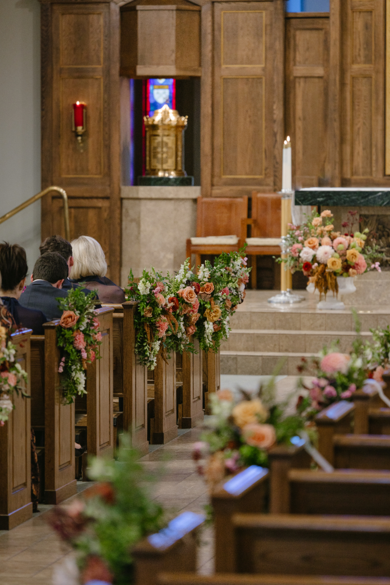 Our Lady of the Mountains Catholic Church in Jackson Hole decorated for an elegant autumn wedding, with seasonal floral arrangements lining the pews.