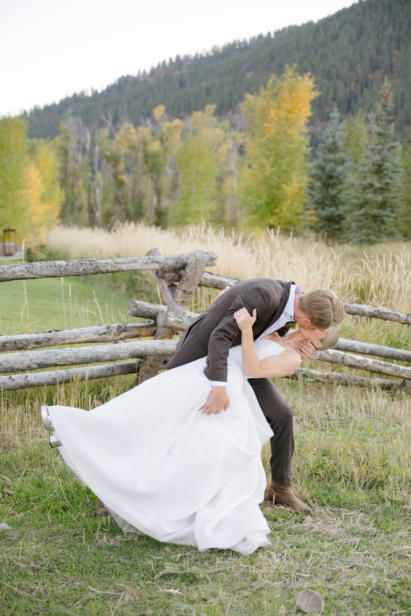 Bride and groom sharing a romantic dip kiss during golden hour portraits at Snake River Sporting Club