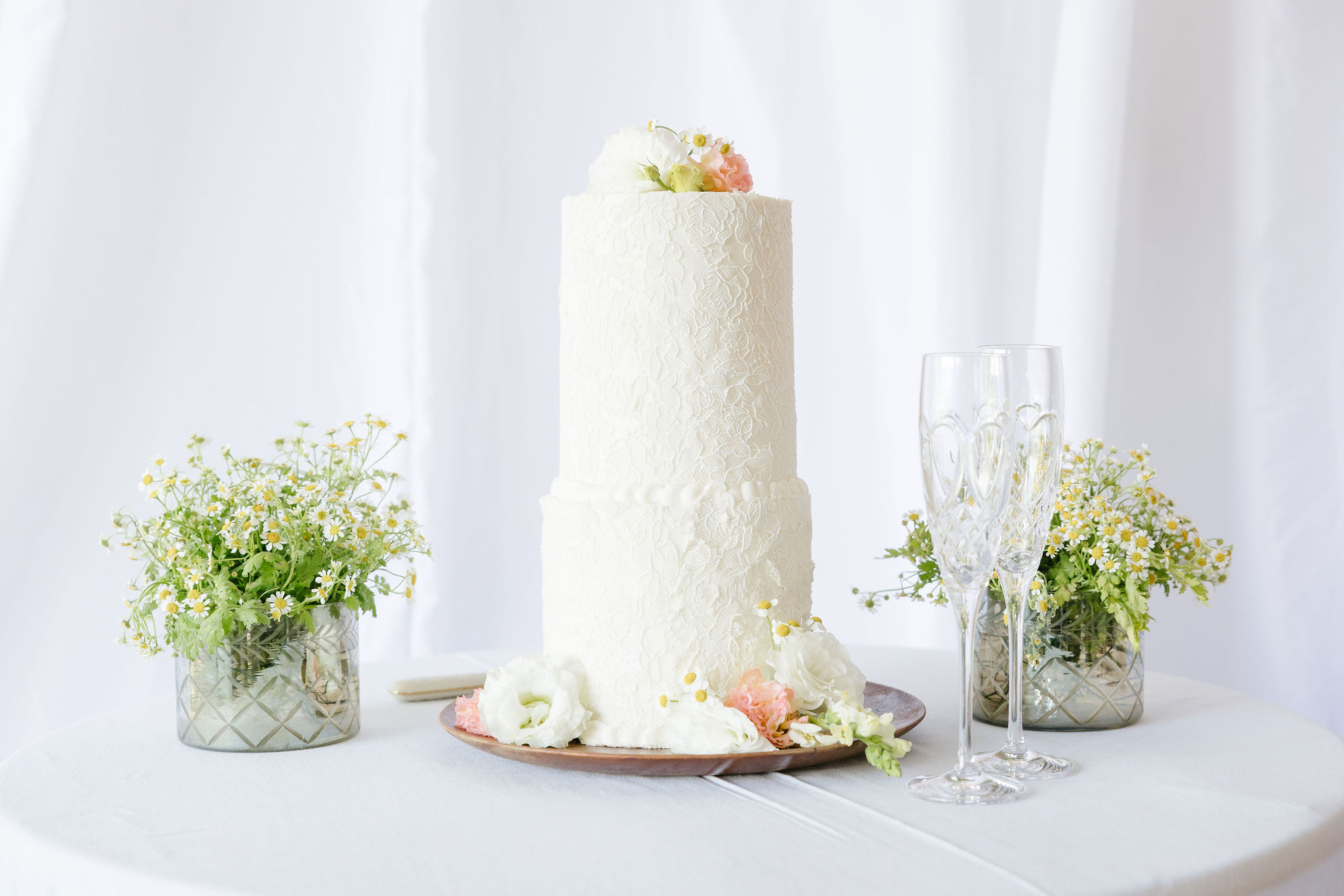 White wedding cake with textured icing, fresh florals, and crystal champagne flutes at a Jackson Hole wedding.