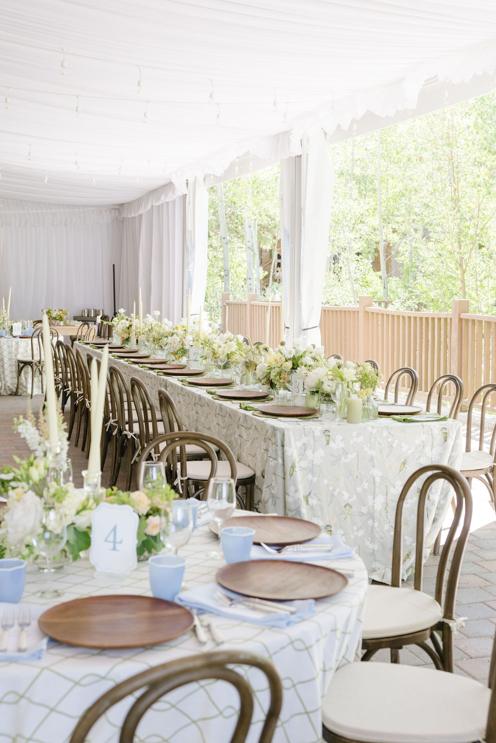 Elegant tented wedding reception with white draping, floral tablescapes, and woodland views in Jackson Hole.