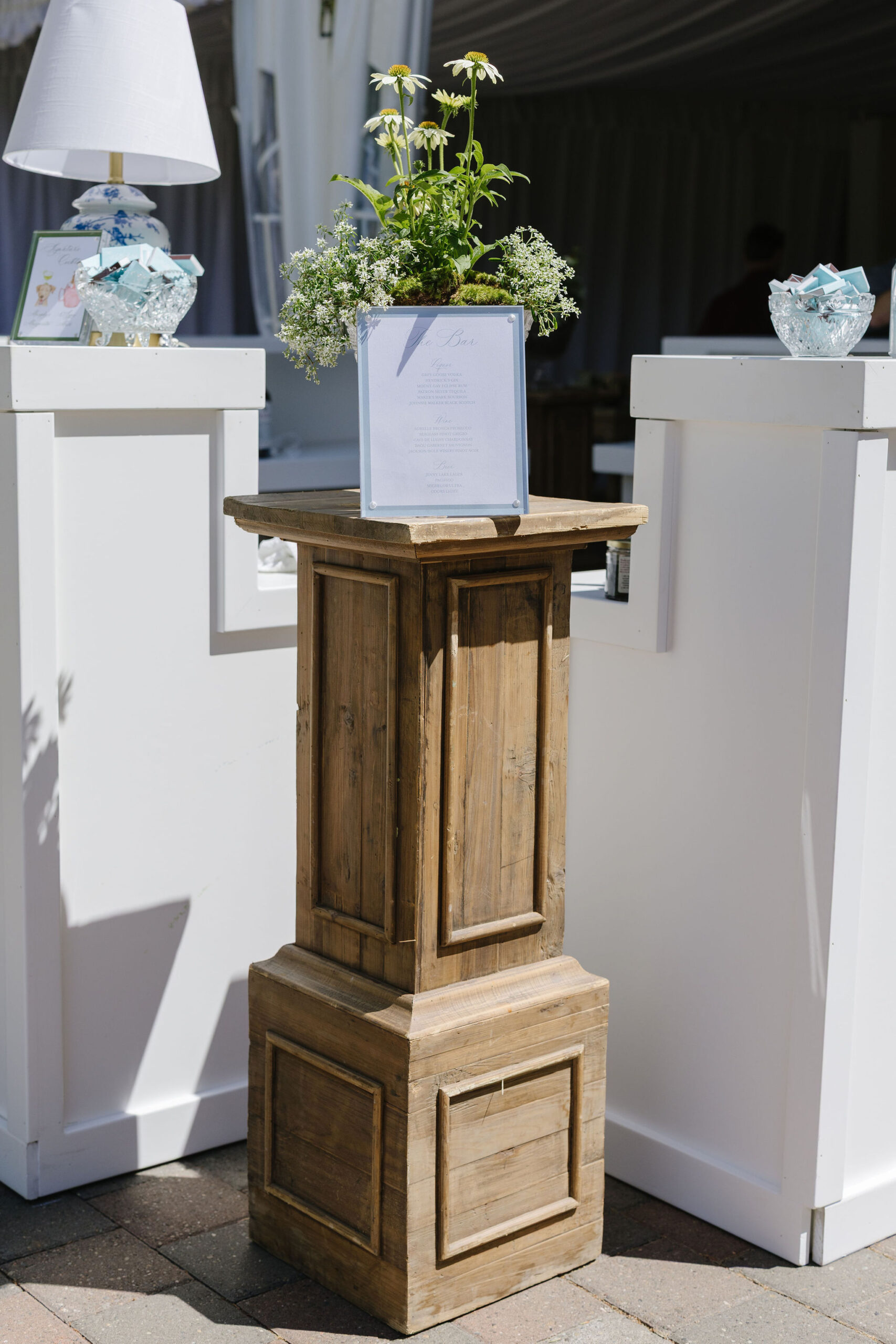 Wedding bar menu displayed with fresh flowers and elegant decor at a blue and green wedding reception.