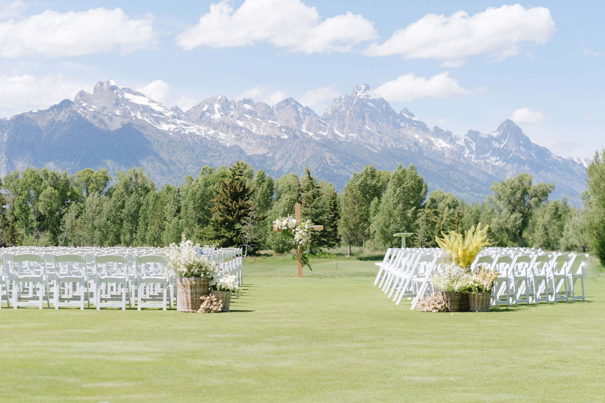 Wedding ceremony set up with white chairs and lush florals looking out onto the Tetons.