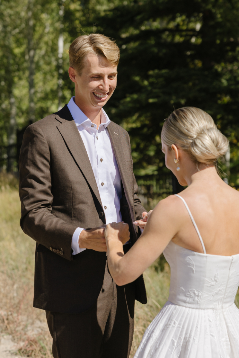 Groom smiles at bride as he reacts during their first look at Snake River Sporting Club.