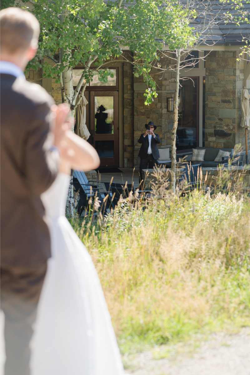 A shot of the bride's father taking a photo of the bride and groom during their first look.