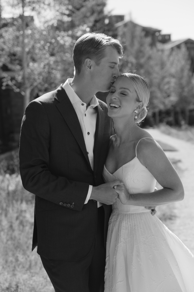 Black and white photo of groom kissing bride on the top of her head as they have their first look at Snake River Sporting Club.