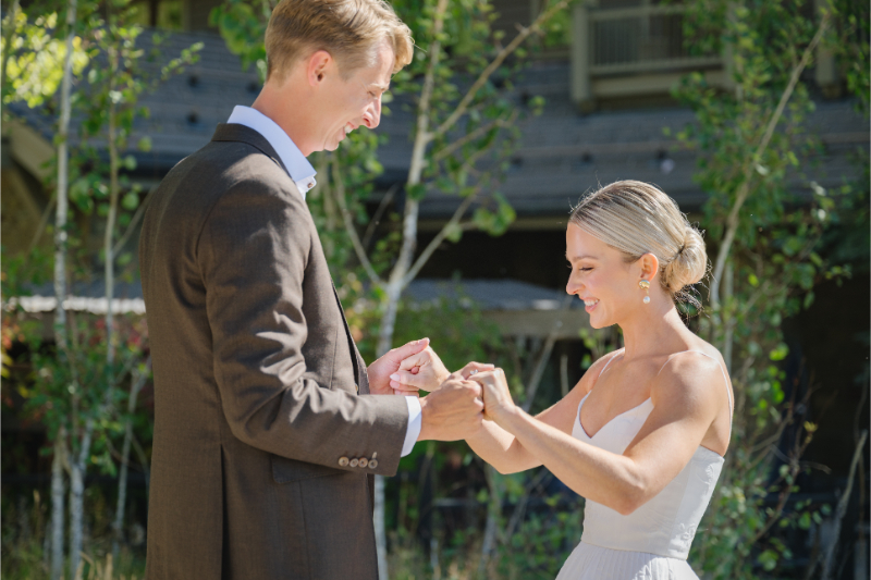Bride and groom holding hands and smiling as they look at each other lovingly during their first look.