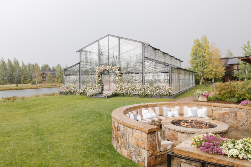 Wedding ceremony ideas showcasing a glass conservatory reception venue with floral installations in Jackson Hole.