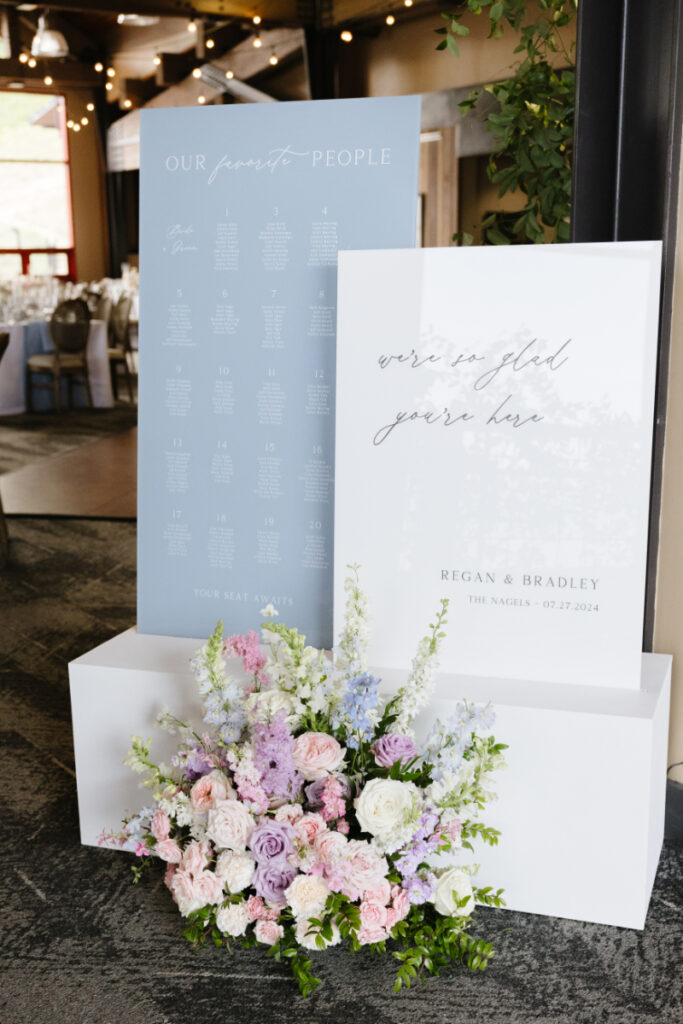 Pastel wedding welcome sign and seating chart with floral arrangement