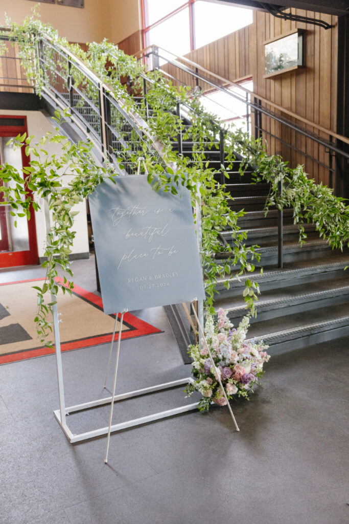 Wedding welcome sign decorated with greenery and pastel flowers